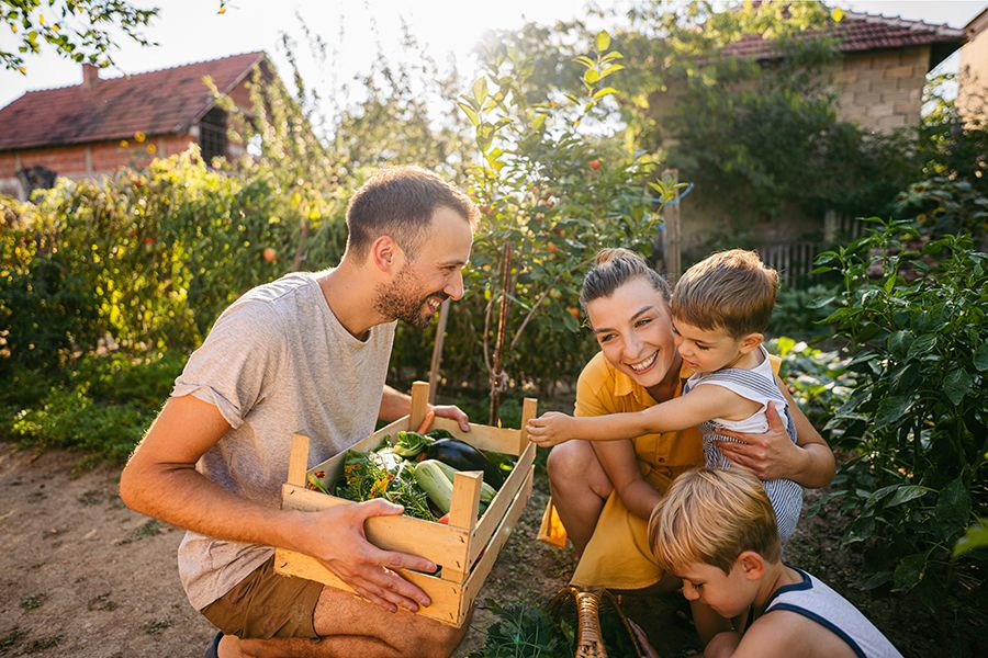 A family smiling in their garden under the sun.