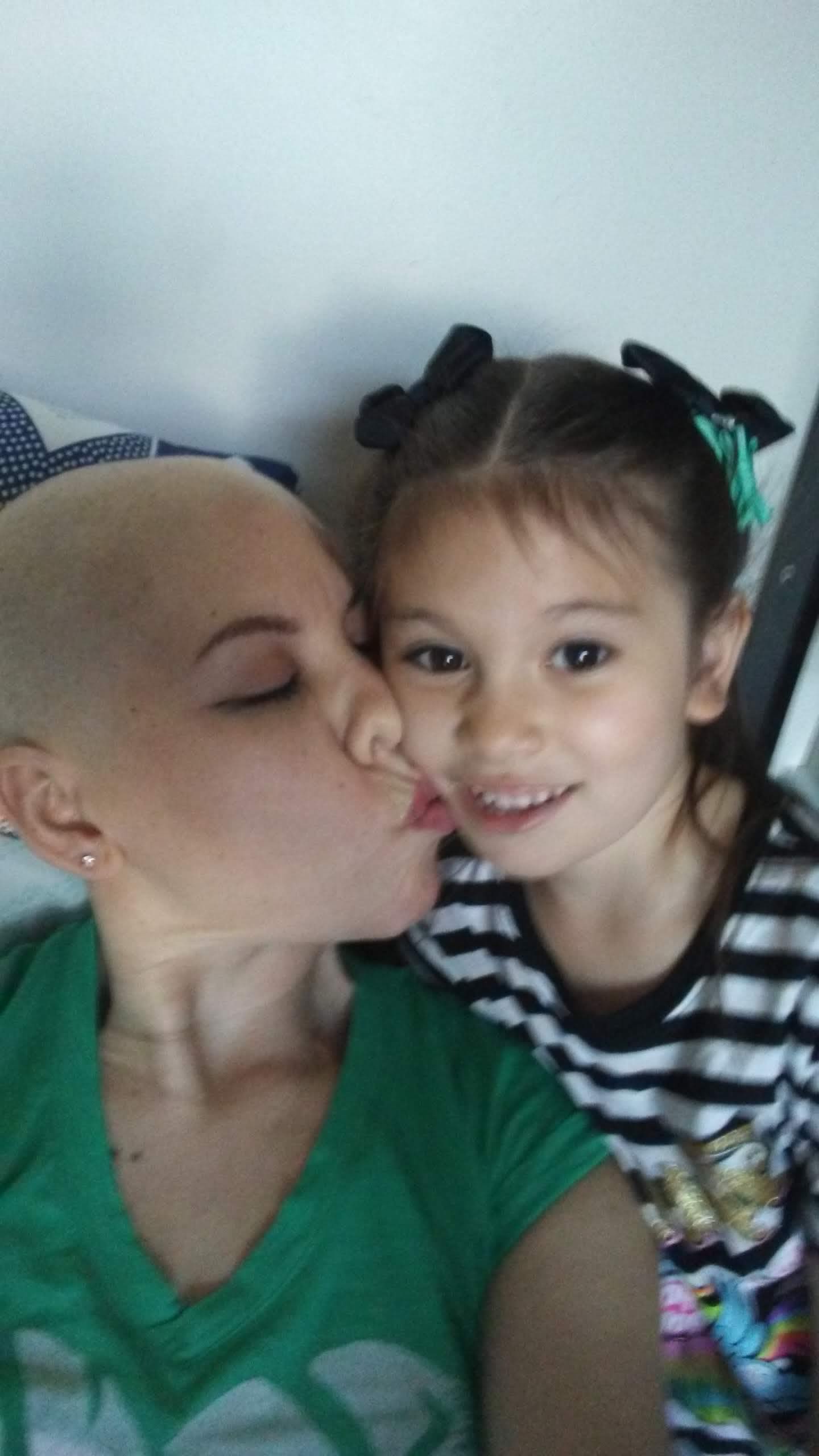 A mother kissing her daughter. 