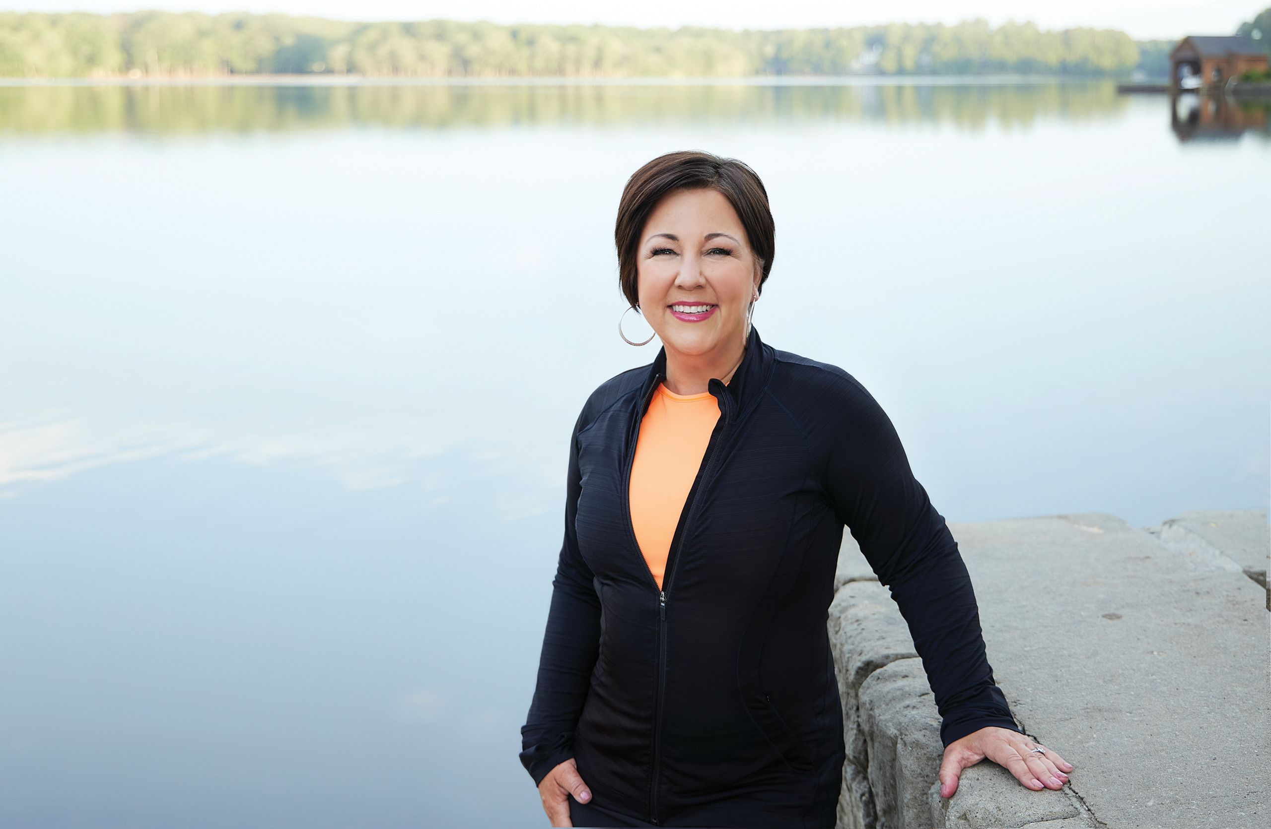 A woman with metastatic breast cancer posing near a lake.