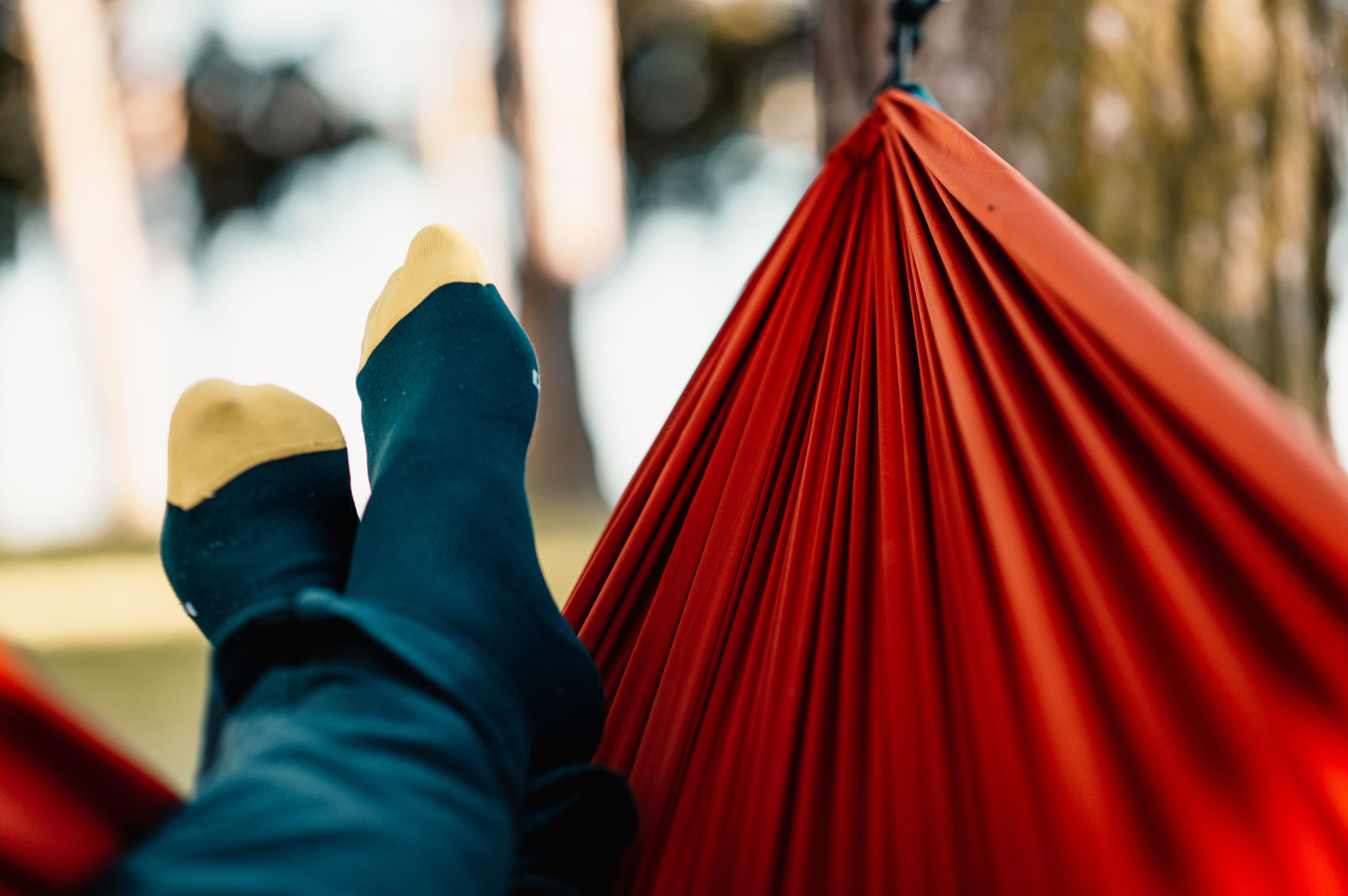 A person with gout laying in a hammock outside in nature.
