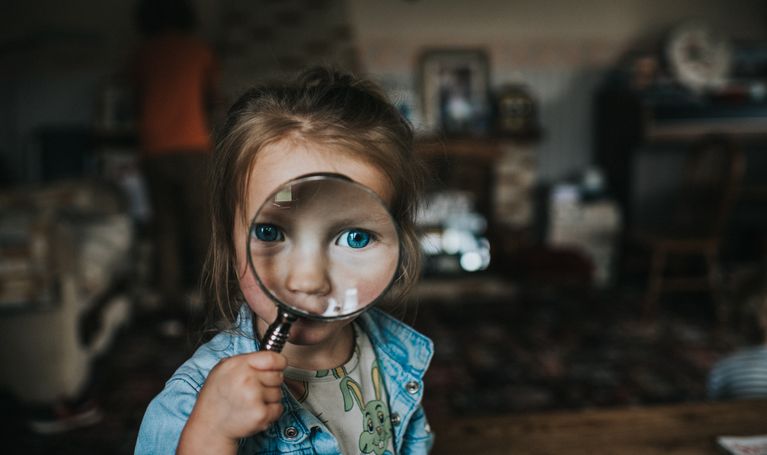 A child with a magnifying glass over her eyes.