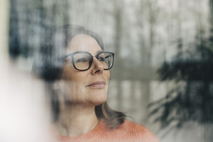 A woman with Graves Disease wearing glasses and looking out the window. 
