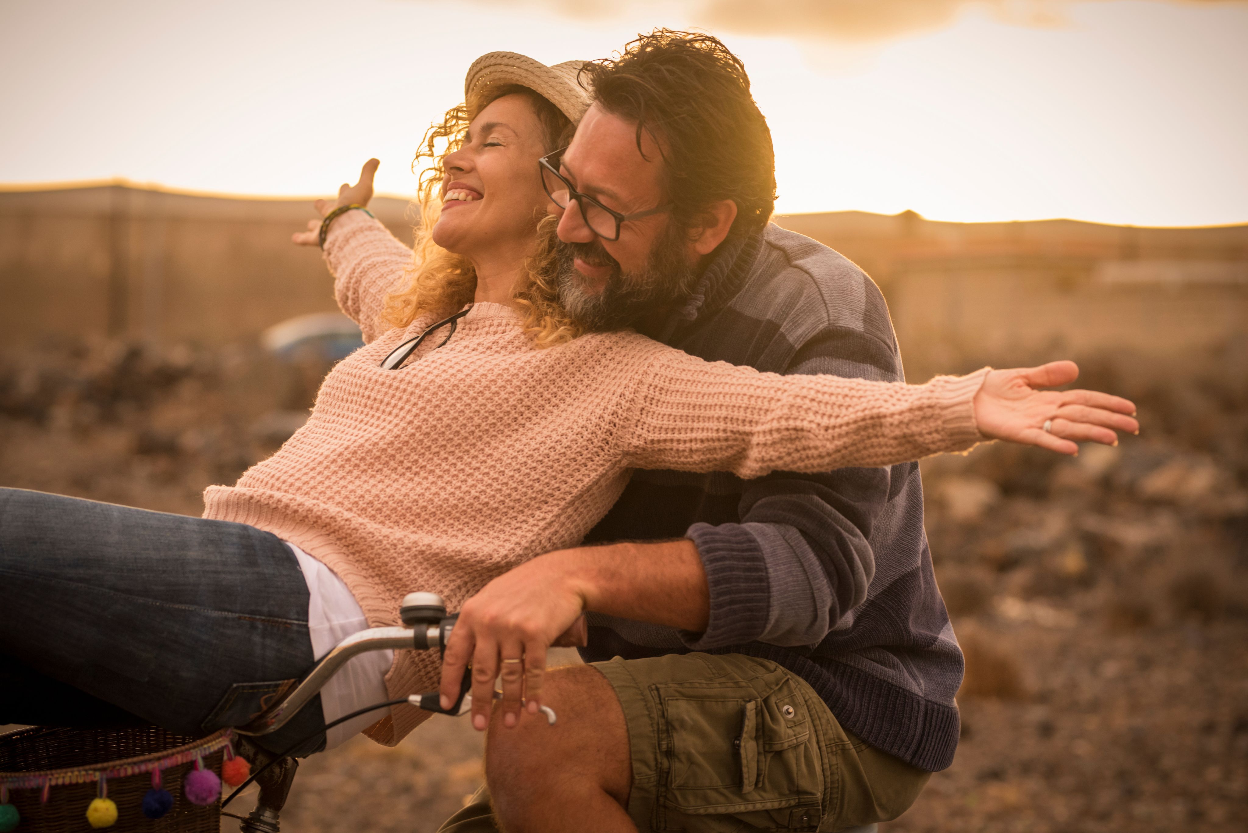 A man and wife smiling and riding a bike.