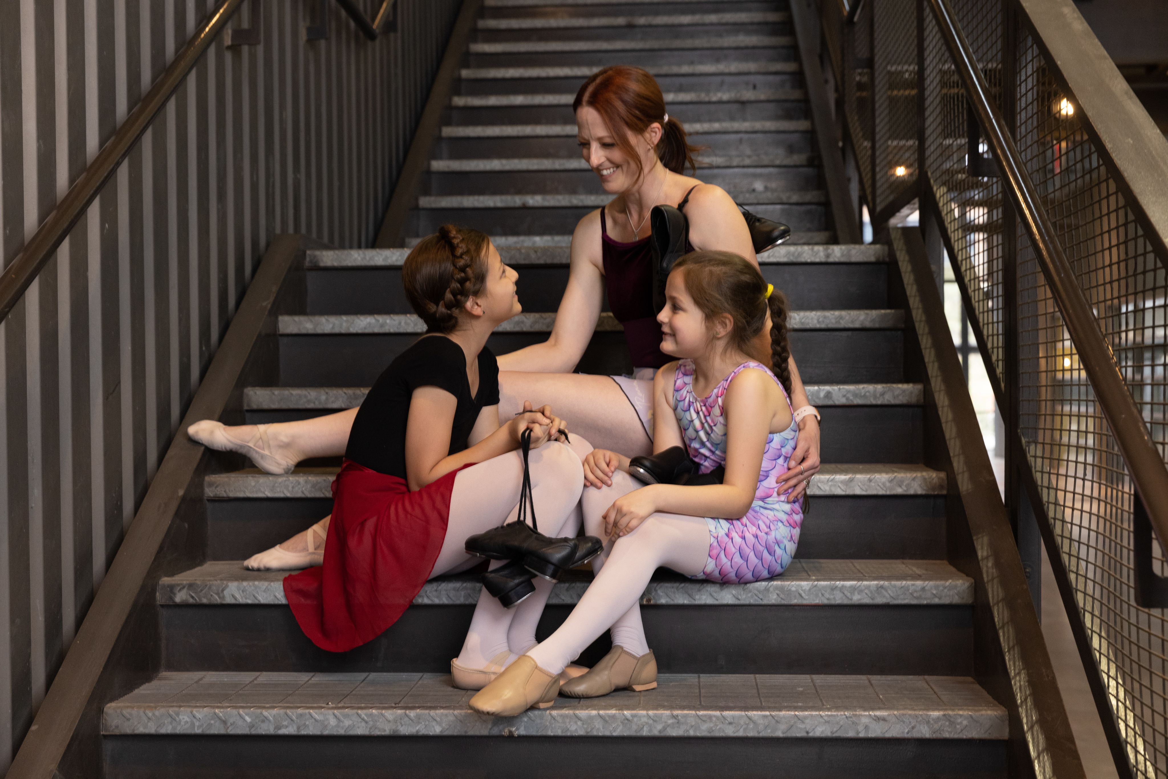 A dance teacher smiling at her two students. 