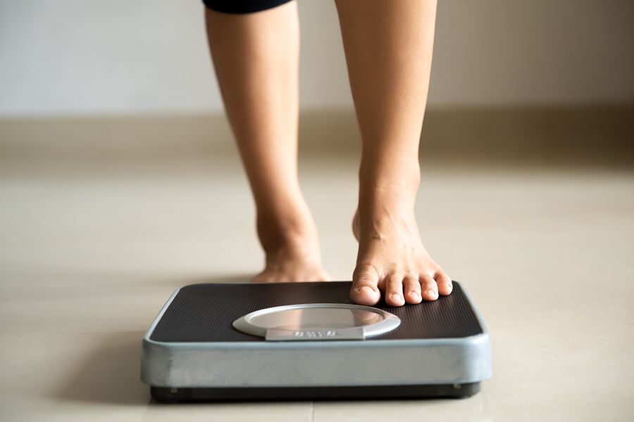 An individual stepping on a scale for their weekly weigh-in.