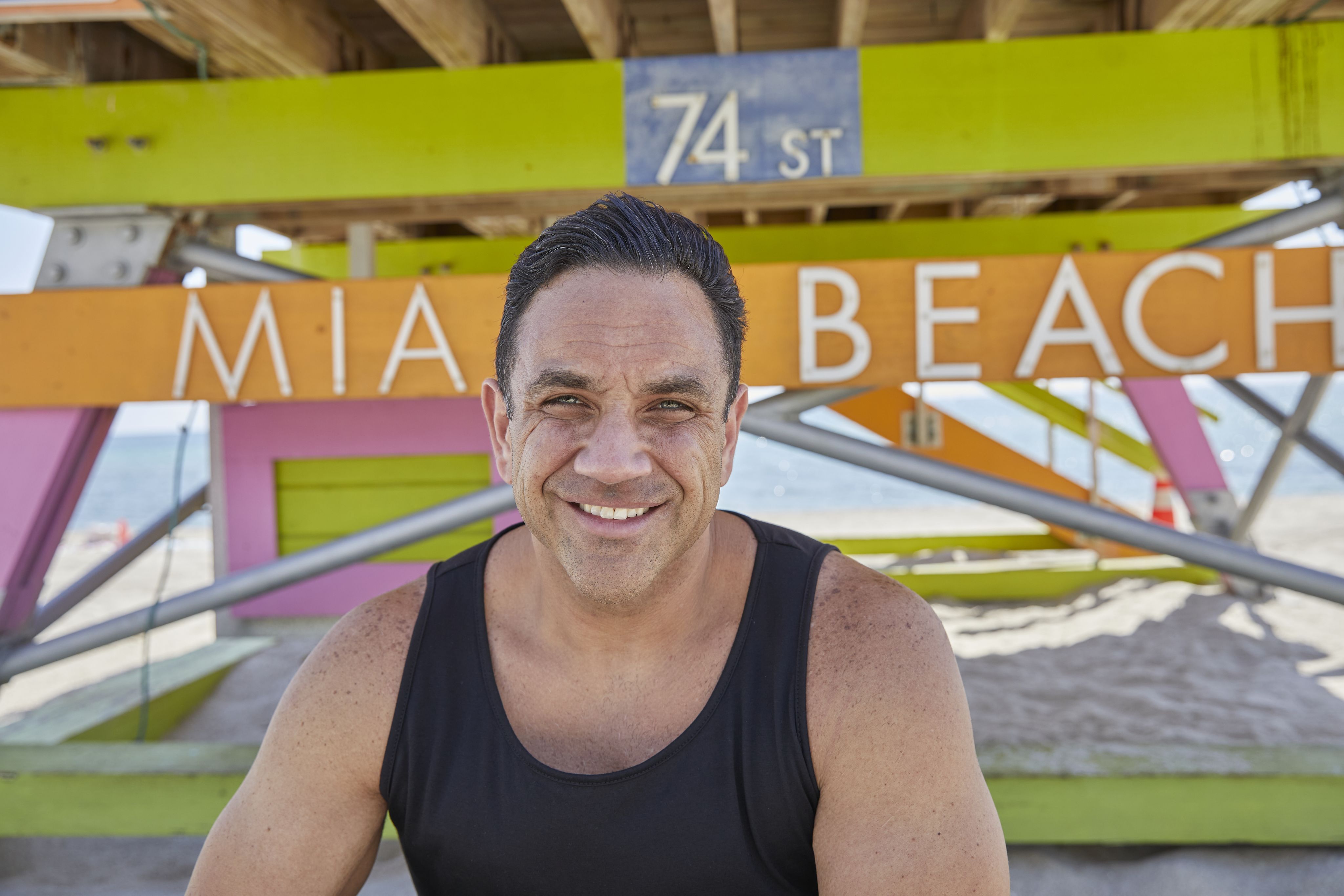 A man outside at the beach smiling.