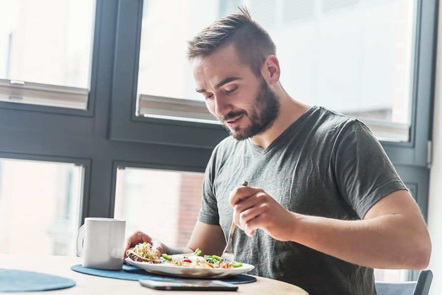A man sitting and eating a healthy breakfast to promote long-term weight maintenance. 