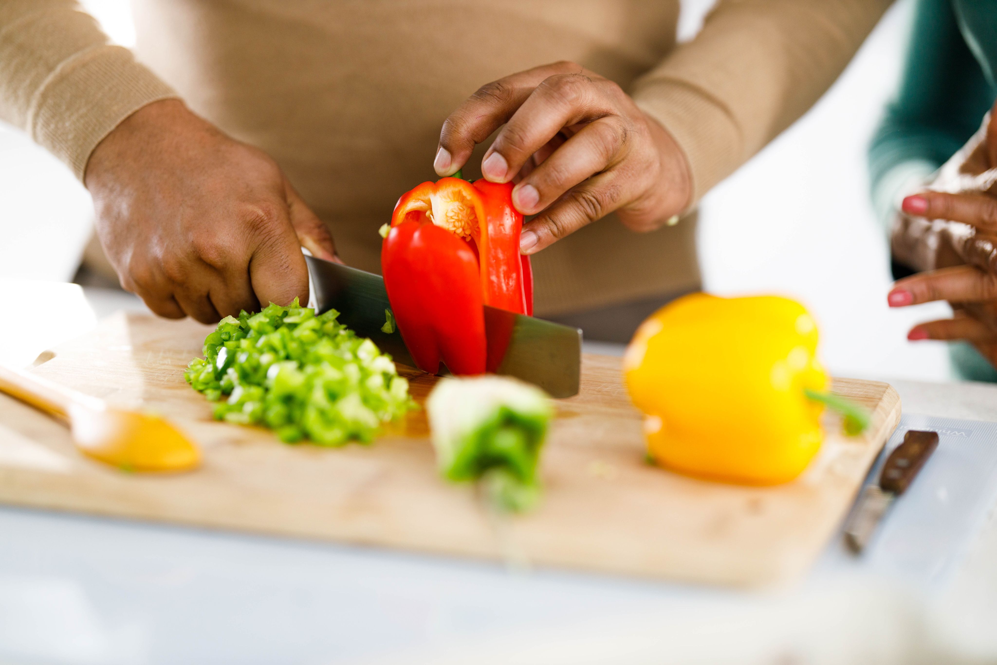 Hands chopping a red bell pepper