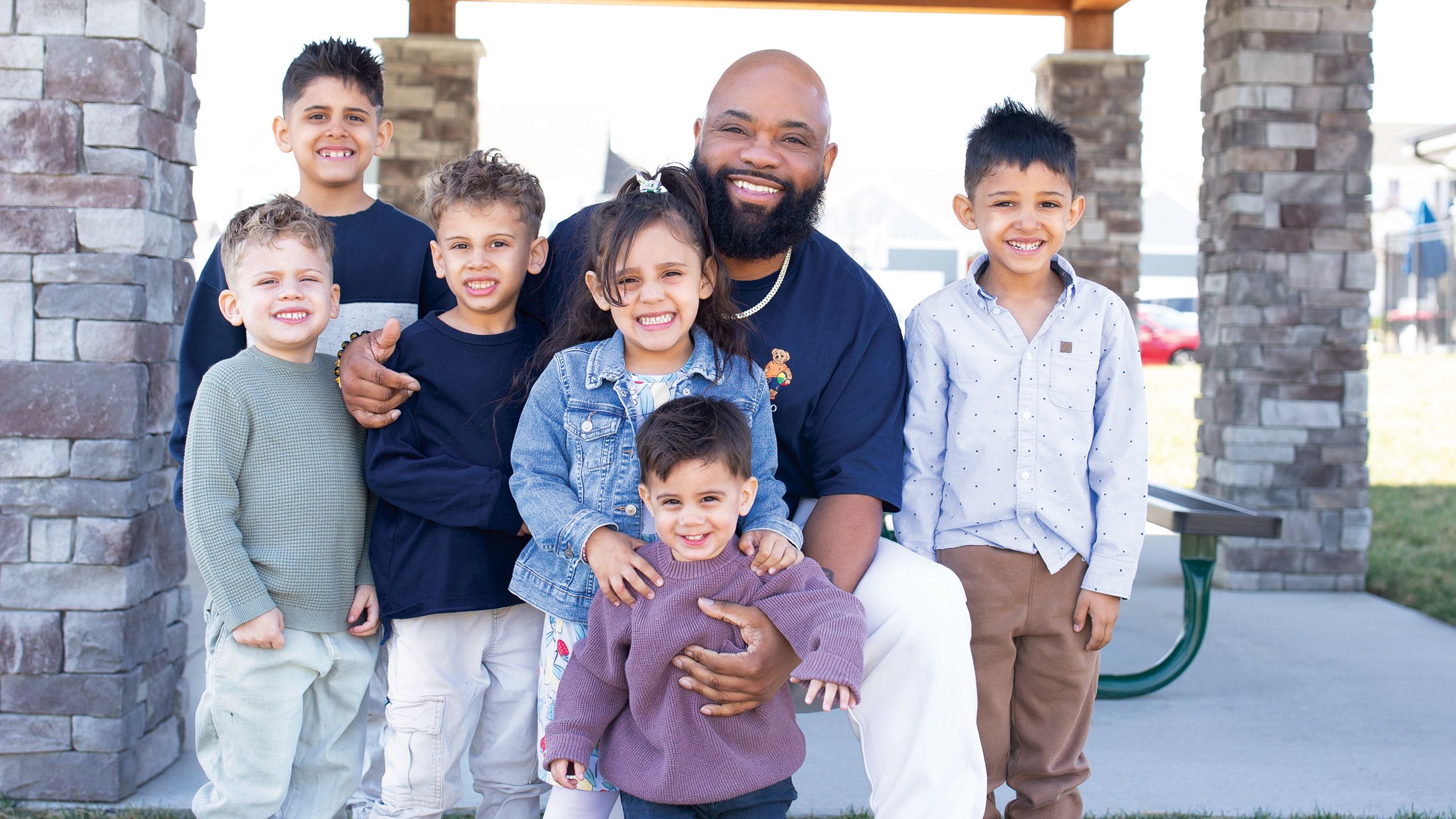 Man surrounded by a group of young children smiling
