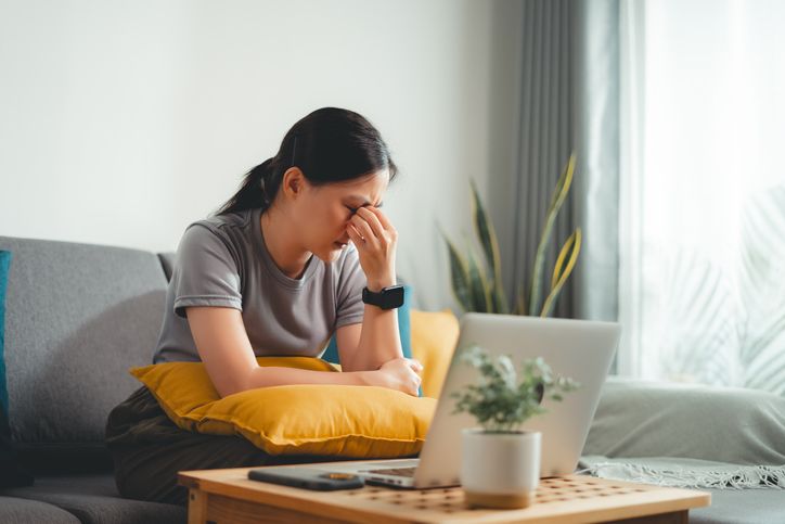 An image of a woman working on her computer with head pain.