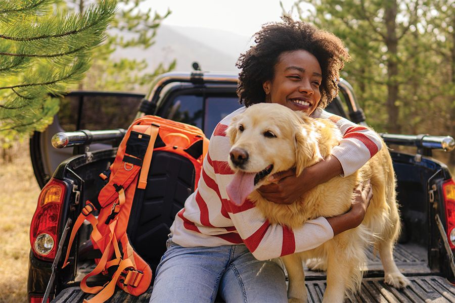 An image of a woman with graves disease smiling with her dog outside.