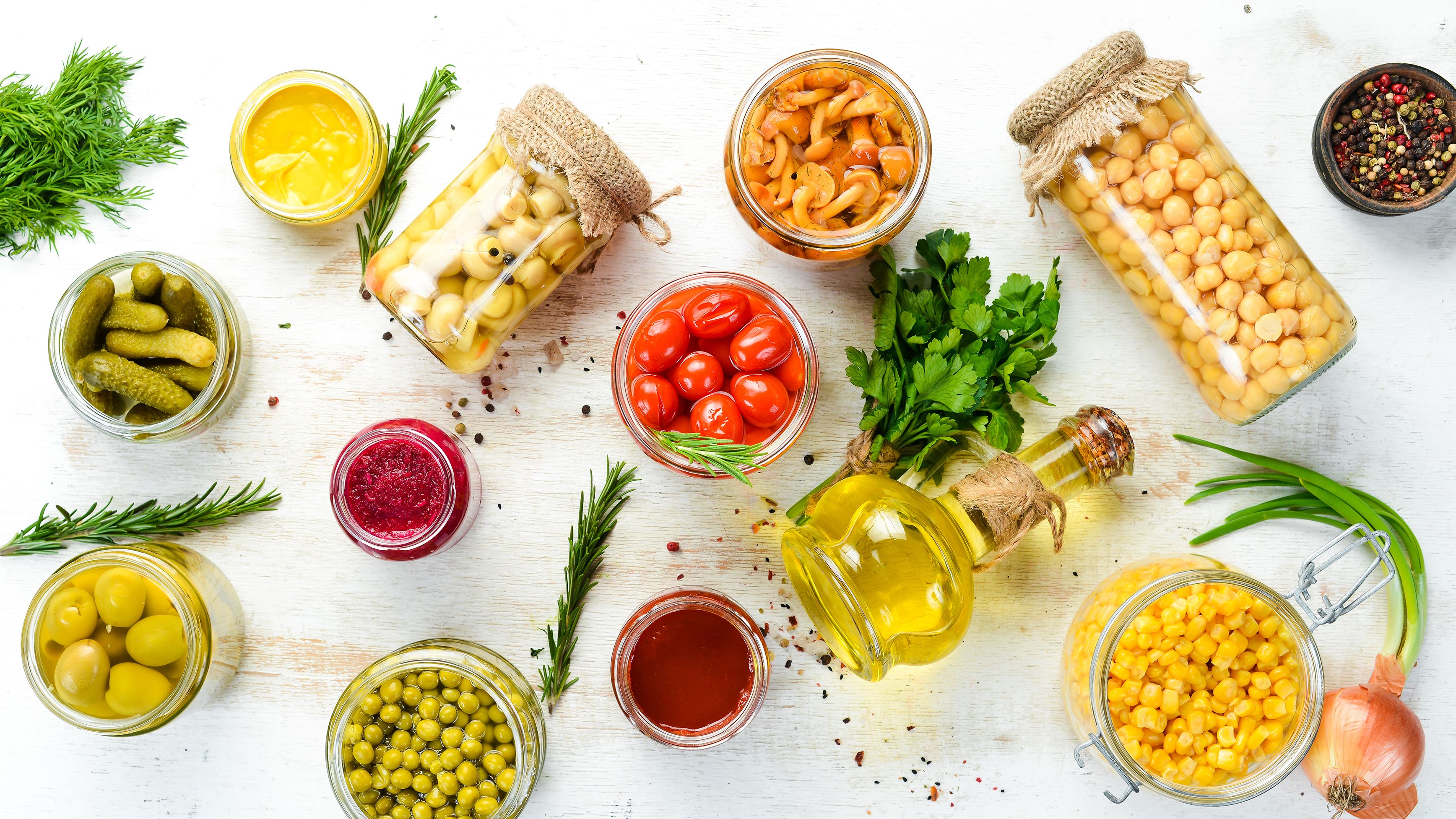 A photo of items you should keep in your pantry for heart health. (Chickpeas, tomatoes, oil, corn, pickles.)