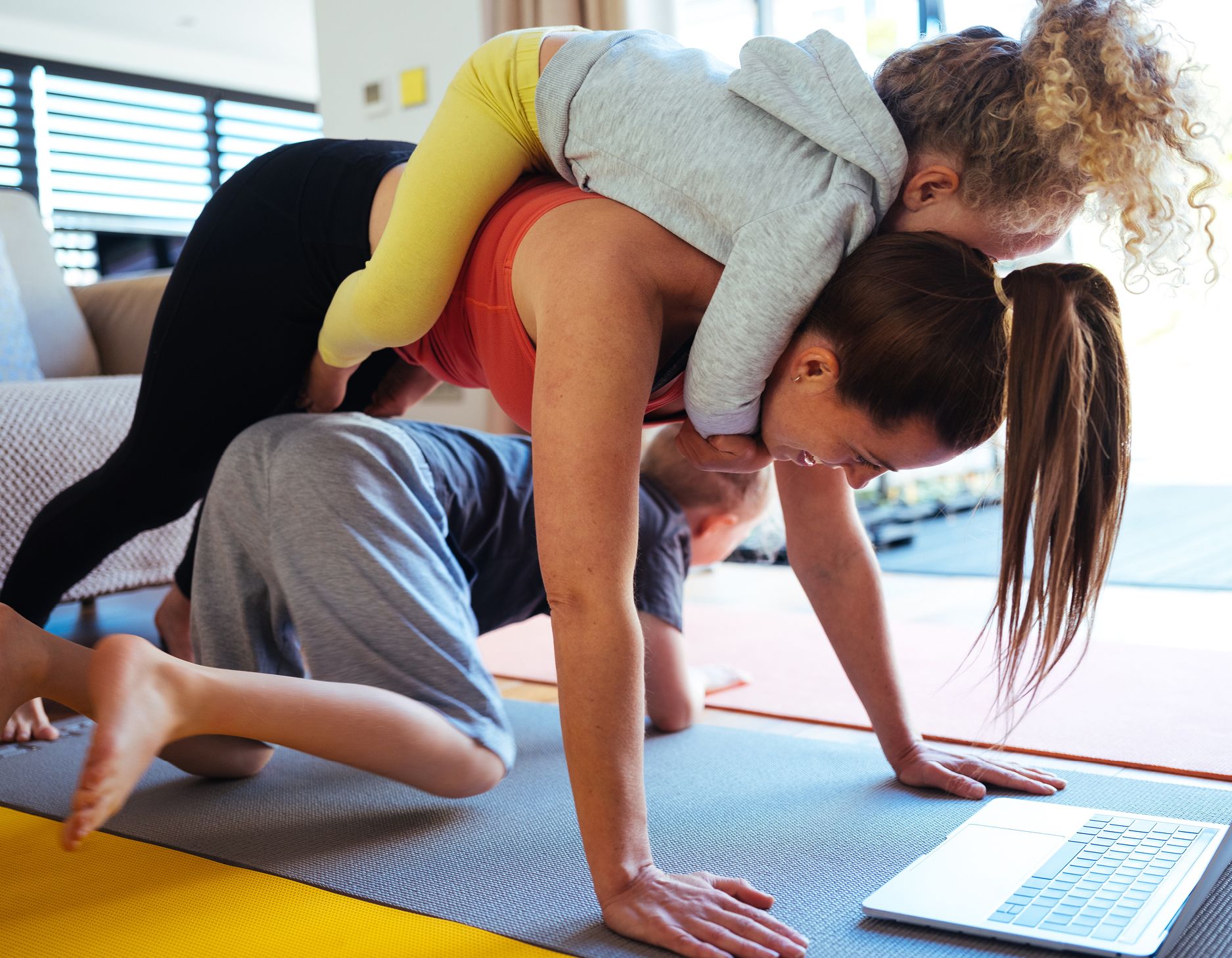 A woman and her children having fun doing yoga at home.
