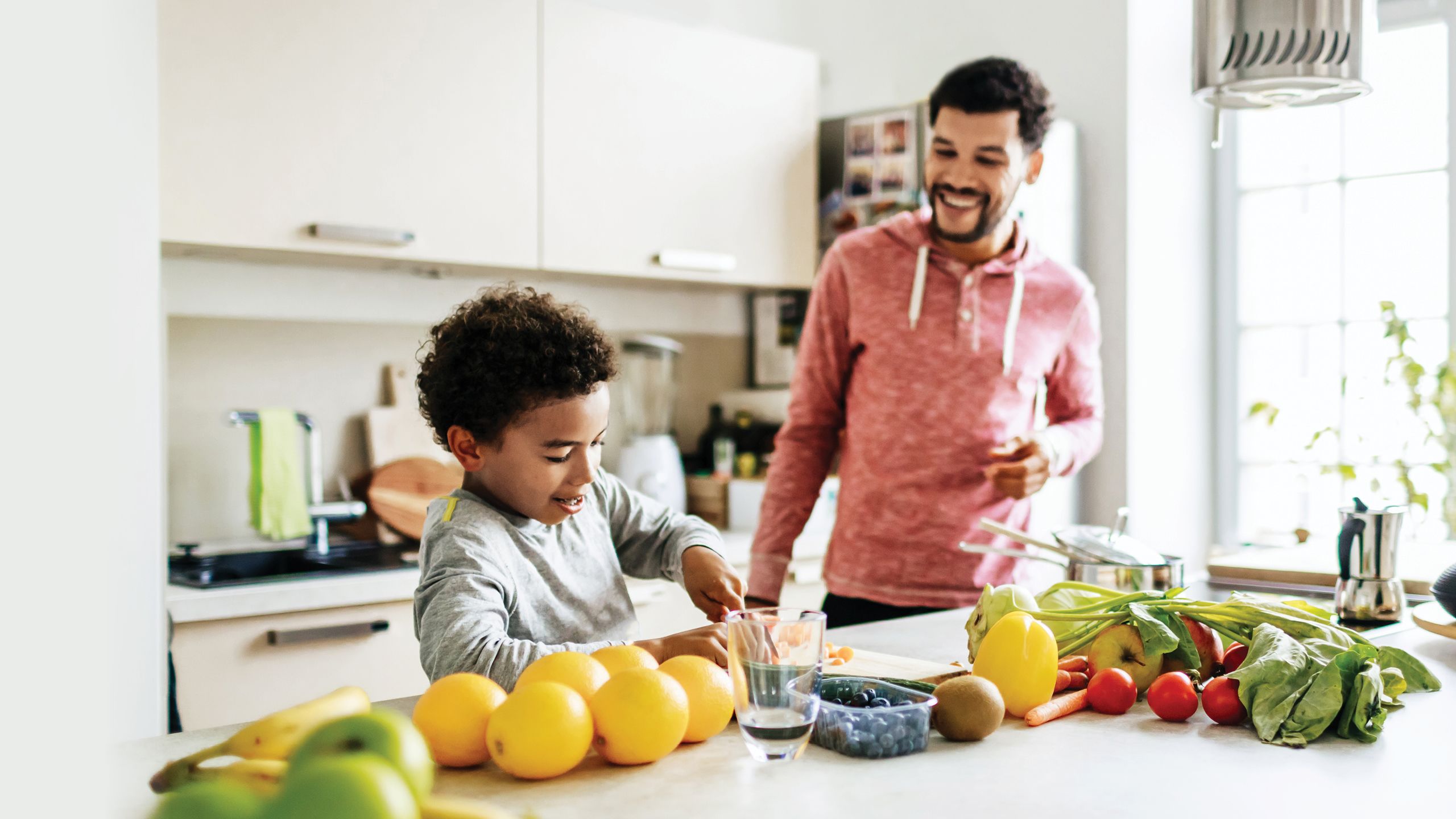 A father and son in the kitchen cooking heart-healthy food to keep cholesterol low.