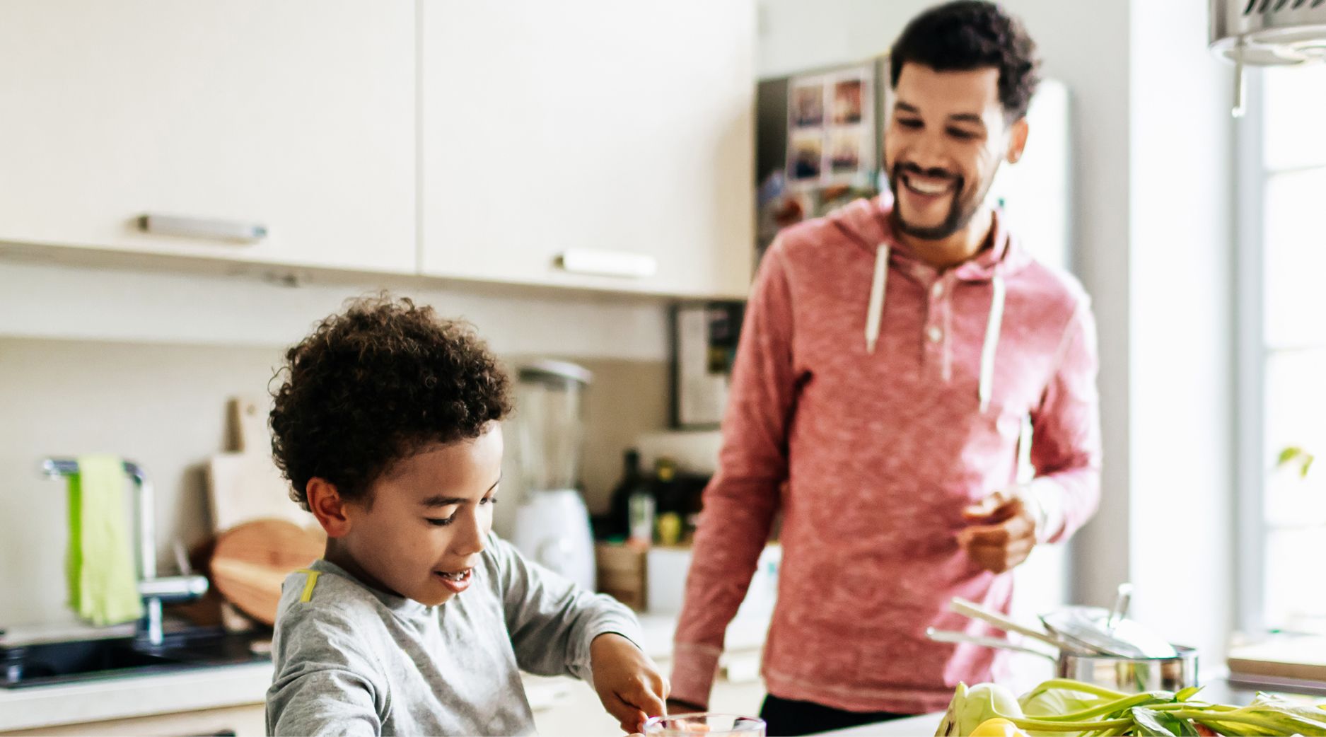 A father and son in the kitchen cooking heart healthy food to keep cholesterol low.