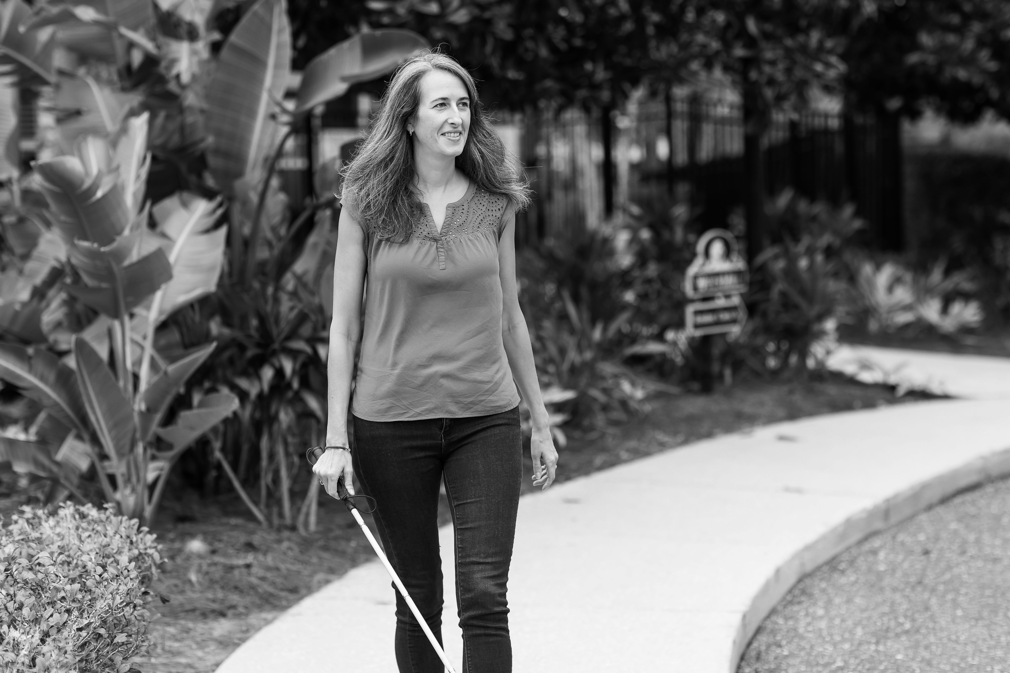 Woman walking along path with cane.