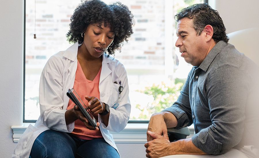 An image of a dermatologist explaining treatment to a man with plaque psoriasis.