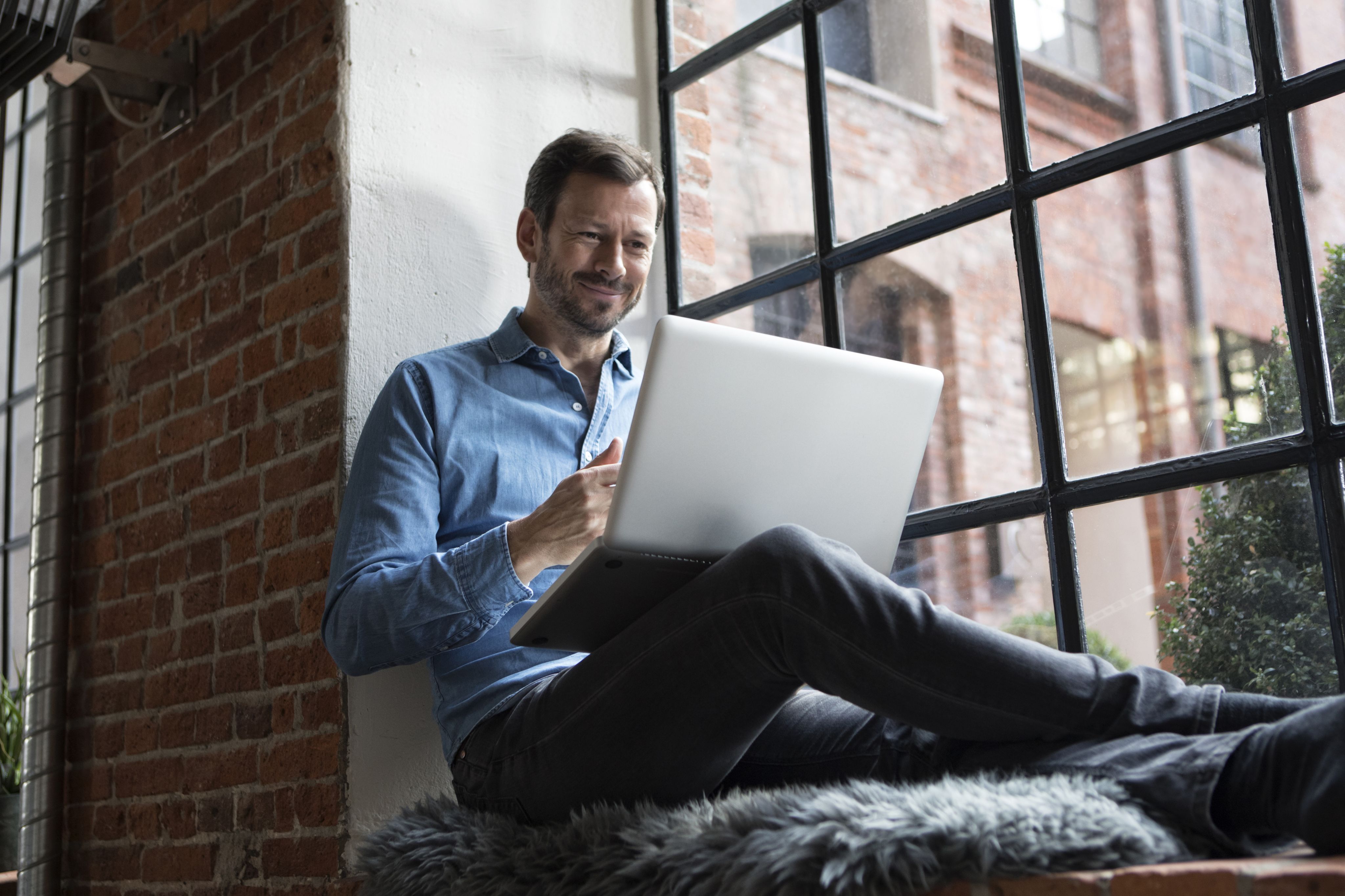 A man smiling and using his laptop.