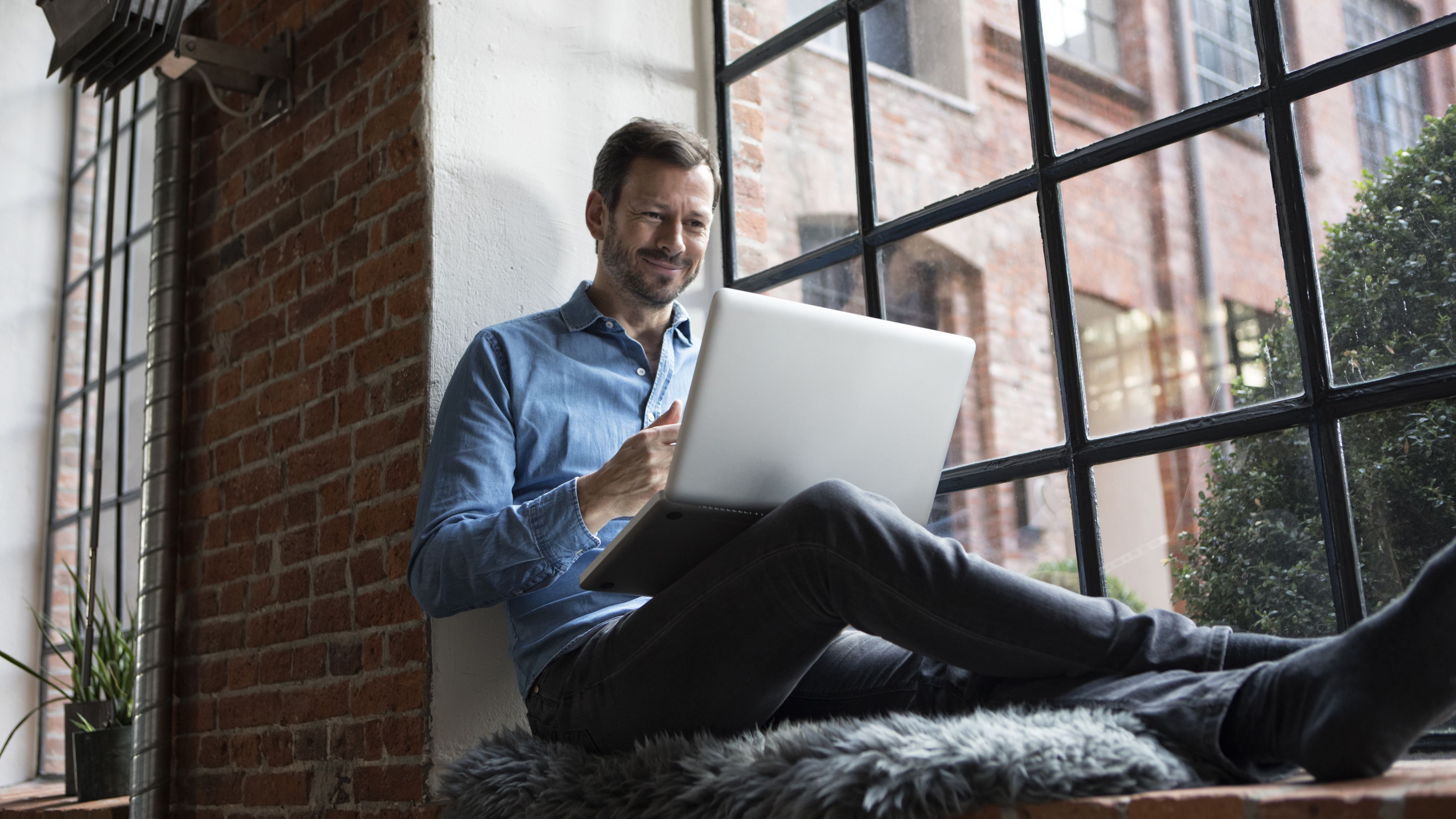 A man smiling and using his laptop.